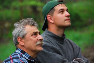 older dad and grown son looking up toward sky